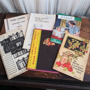 May include: A collection of vintage home canning books with colorful covers and titles like "Home Canning of Fruits and Vegetables", "The Home Canners Text Book", and "The Home Canners Year Book 1929".