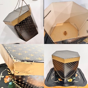 May include: A vintage black and gold hexagonal box with a fleur-de-lis pattern. The box has a gold trim and a rope handle. The interior is beige. The box is displayed on a black tray with floral designs.