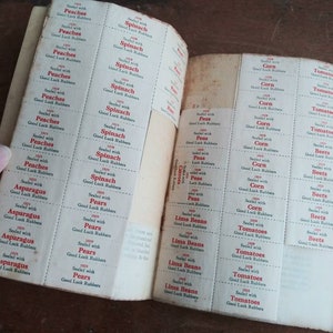 May include: A vintage book of Good Luck Rubber bands for produce. The book has pages of labels for different fruits and vegetables, including peaches, spinach, pears, asparagus, corn, tomatoes, peas, lima beans, and beets. Each label has the year 1929 and the text "Sealed with Good Luck Rubbers".