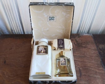 Puede incluir: Un set de regalo en una caja negra y blanca con una tapa blanca. La caja contiene un frasco de perfume Yardley Lavender, un frasco de sales de baño Yardley Lavender y una pastilla de jabón Yardley Lavender. La caja está decorada con un patrón floral.