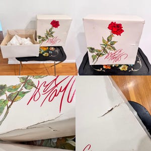 May include: White box with a red rose illustration and red script. The box is sitting on a black tray with a floral design. Another box is open, revealing white tissue paper.