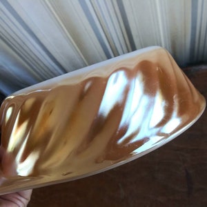 May include: A gold and white ceramic baking dish with a fluted design. The dish is made of a shiny, iridescent material.