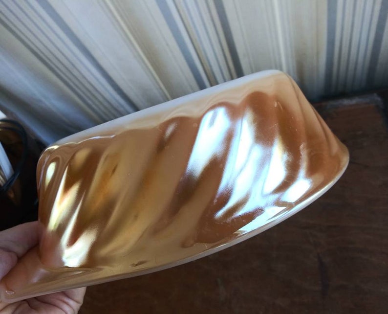 May include: A gold and white ceramic baking dish with a fluted design. The dish is made of a shiny, iridescent material.