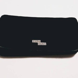 May include: A black velvet clutch with a silver rhinestone lightning bolt design.