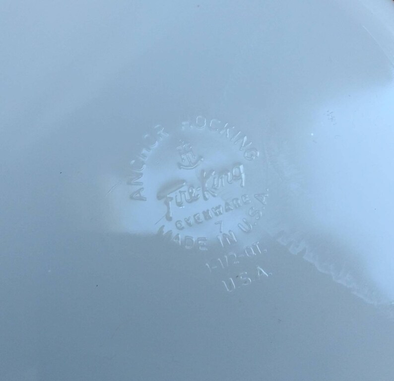 May include: A white Fire King Ovenware Anchor Hocking 7 inch round dish with a blue and white floral design. The bottom of the dish has the Fire King logo and the words "Ovenware" and "Made in USA".