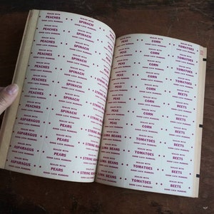 May include: A vintage book of labels for canning jars. The labels are printed in red and white and feature a variety of fruits and vegetables, including peaches, spinach, peas, corn, tomatoes, beets, asparagus, pears, string beans, and lima beans.