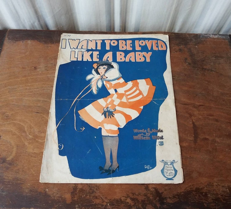 May include: Vintage sheet music cover featuring a woman in a striped dress with a white fur collar. The title of the song is "I Want to Be Loved Like a Baby" with the words and music credited to William Witti.