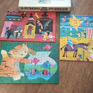 May include: Three colorful jigsaw puzzles featuring a cat with a fishbowl, a beach scene with children, and a circus scene with animals. The box reads "3 Jumbo Jig Saw Puzzles".