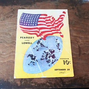 Könnte beinhalten: Ein Vintage-Programm in Gelb und Weiß für ein Footballspiel zwischen Peabody und Lowell. Das Programm zeigt ein stilisiertes Bild eines Footballspiels mit Spielern in Aktion. Das Programm zeigt auch eine große amerikanische Flagge im Hintergrund. Das Programm ist datiert auf den 28. September 1947 und kostet 10 Cent.