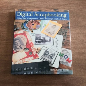 May include: Book cover with the title "Digital Scrapbooking: Using Your Computer to Create Exciting Scrapbook Pages" by Maria Given Nerius. The cover features a collage of images, including a vintage typewriter, a keyboard, and various photographs.