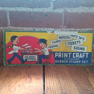 Puede incluir: Caja de juego de sellos de goma Print Craft vintage. La caja presenta una colorida ilustración de dos hombres de dibujos animados, uno etiquetado "BOSS", con texto que dice "We Print Anything", "Notices", "Cards", "Posters", "Price Tags", "Tickets" y "Signs".