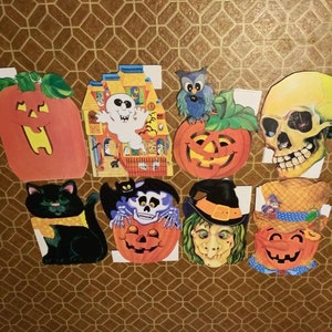 May include: A set of nine Halloween decorations featuring a variety of spooky characters and themes. The decorations include a pumpkin, a ghost, a skull, a witch, a black cat, a scarecrow, and a haunted house. The decorations are made of cardboard and are printed with colourful images.