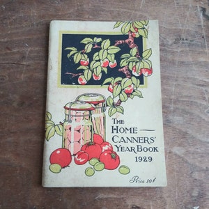 May include: Vintage book cover with a red, green, and black illustration of jars of fruit and a branch of apples. The title is "The Home Canners' Year Book 1929" with the price "Price 10&cent;".
