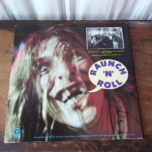 May include: A vintage vinyl record album cover featuring a close-up of a man's face with an open mouth and tongue sticking out. The album title is "Raunch 'N' Roll" in a speech bubble. The back of the album cover shows a band in a photo.