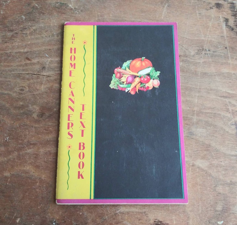 May include: The Home Canners Text Book with a yellow cover and a black background featuring a colorful illustration of various vegetables and fruits.