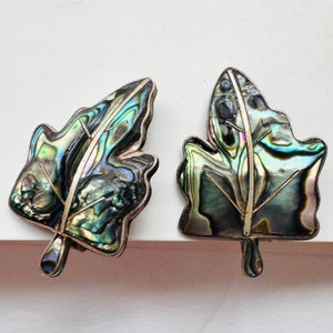 May include: A pair of silver earrings shaped like leaves, with iridescent abalone shell inlay.
