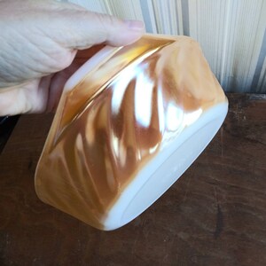May include: A vintage iridescent glass bowl with a swirl pattern in shades of peach and white.