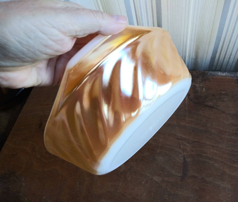 May include: A vintage iridescent glass bowl with a swirl pattern in shades of peach and white.