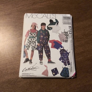 Op de afbeelding: Een McCall's naaipatroon voor kinderkleding. Het patroon is voor de maten 10, 12 en 14. Het patroon bevat instructies voor het maken van een overall, een T-shirt en een hoed. Het patroon is geïllustreerd met een tekening van een jongen en een meisje die de kleding dragen.