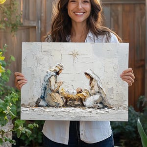 May include: A textured painting depicts the Nativity scene. Joseph and Mary kneel beside the baby Jesus in a manger, under a star. The artwork uses a palette of white, beige, and blue tones, creating a serene and reverent atmosphere.