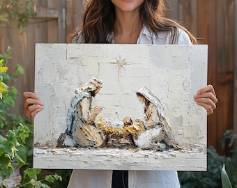 May include: A rectangular canvas painting featuring a textured impasto nativity scene. The artwork depicts two figures kneeling on either side of a central manger containing a small infant, with a star positioned above them in a white, cream, and gold palette.