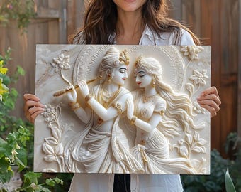 Puede incluir: Una placa de pared rectangular que presenta una escultura en alto relieve blanca y dorada de las deidades Radha y Krishna. Krishna aparece tocando una flauta, mientras Radha está a su lado. La escena está enmarcada por motivos florales.