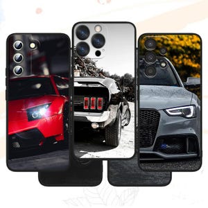 以下が含まれることがあります： 自動車のデザインが施された3つの長方形のスマートフォンケース。左のケースは赤いスポーツカーのフロント、中央のケースは黒いクラシックカーのリア、右のケースはハニカムグリルを備えたグレーのスポーツカーのフロントが描かれています。