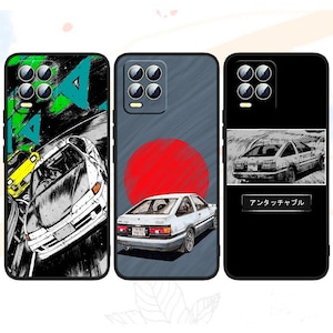 Peut inclure: Trois coques de téléphone avec des motifs de voitures. L'une présente une illustration en noir et blanc d'une voiture sur une piste avec des accents verts et bleus. Une autre a une voiture blanche avec un soleil rouge. La troisième a une illustration de voiture et du texte japonais.