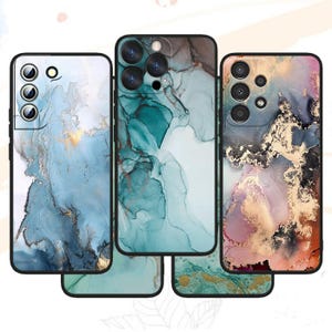 May include: Three rectangular phone cases featuring abstract alcohol ink designs. The left case is blue and white with gold accents. The center case is teal and white. The right case features a blend of pink, black, and gold metallic textures.