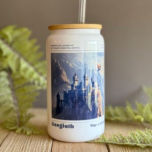 May include: White tumbler with a bamboo lid and a glass straw. The tumbler features a blue and white illustration of a castle with a dragon flying overhead. The text "Training Day, October 1st Only Dragon Riders Will Survive" is printed on the tumbler. The text "Basgiath War College" is printed on the bottom of the tumbler.