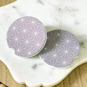 May include: Two gray and white geometric patterned coasters. The coasters have a white outline and a gray background with a white geometric pattern.
