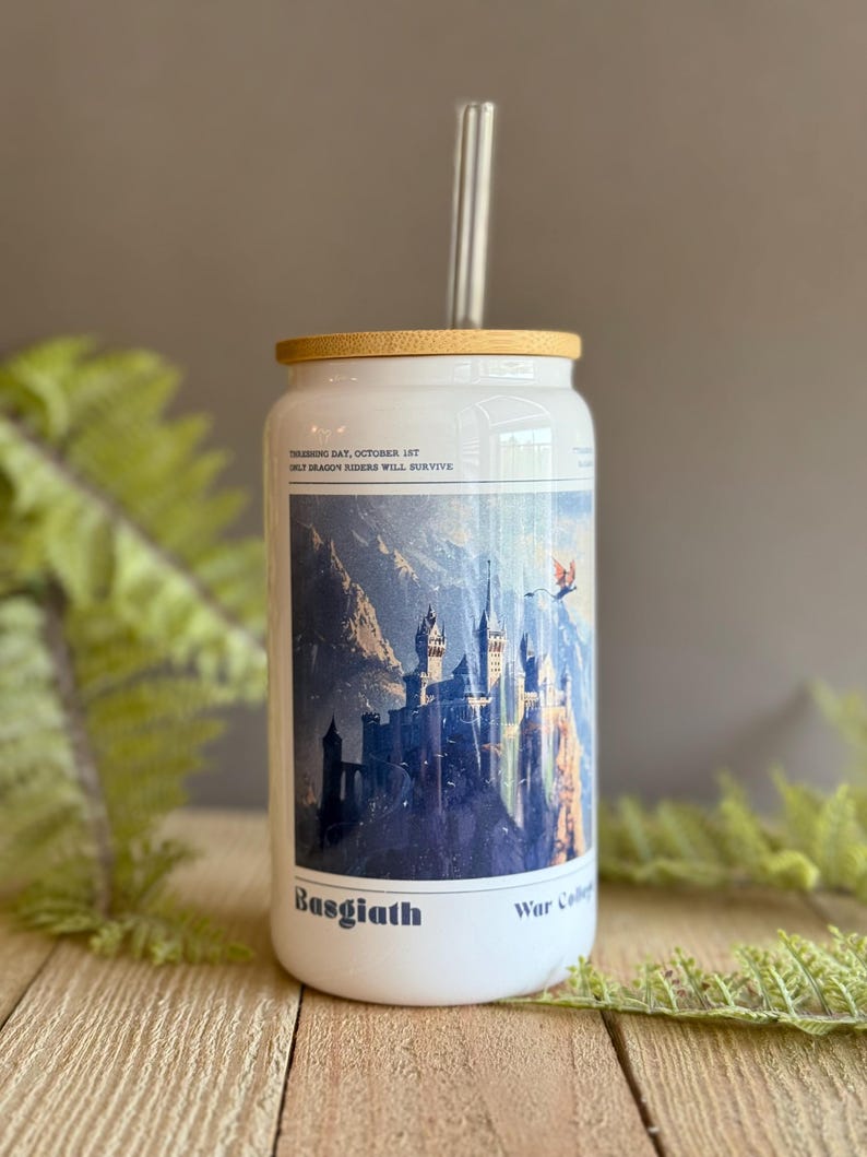 May include: White tumbler with a bamboo lid and a glass straw. The tumbler features a blue and white illustration of a castle with a dragon flying overhead. The text "Training Day, October 1st Only Dragon Riders Will Survive" is printed on the tumbler. The text "Basgiath War College" is printed on the bottom of the tumbler.