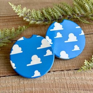 May include: Two round blue and white coasters with a pattern of white clouds on a blue background.