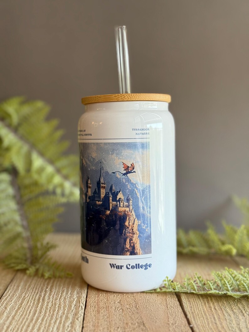 May include: White travel mug with a bamboo lid and a clear glass straw. The mug features a colorful illustration of a castle on a cliff with a dragon flying overhead. The text "War College" is printed on the mug.