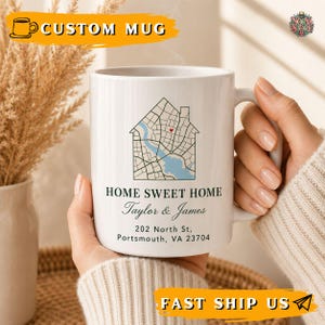 May include: A white ceramic mug featuring a house-shaped map graphic with a small red heart, the text HOME SWEET HOME, the names Taylor & James, and the address 202 North St, Portsmouth, VA 23704 printed in black on the front surface.