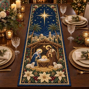 Pode incluir: Um caminho de mesa retangular acolchoado com fundo azul escuro e uma cena de presépio. O design inclui uma estrela central, palmeiras, um estábulo com figuras e flores de poinsétia brancas na borda inferior do tecido.