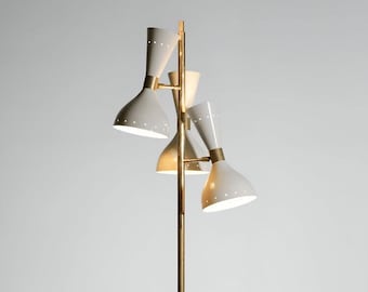 Può includere: Lampada da terra in stile retrò con un'asta in ottone e quattro paralumi bianchi a forma di cono. Ogni paralume ha una fascia in ottone e piccole perforazioni. Un'elegante lampada.