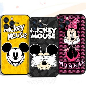 Può includere: Tre custodie per telefono con personaggi Disney. Una è gialla con Mickey Mouse, un'altra è nera con Mickey Mouse che si copre gli occhi, e la terza è nera con Minnie Mouse. Ogni custodia ha un design diverso.