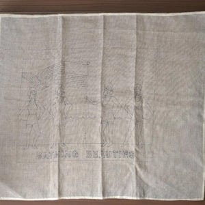 May include: A light beige linen textile featuring an embroidered design of three figures in swimsuits, an American flag, and the words "Bathing Beauties." The textile has a white border.
