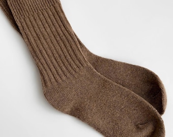 May include: A pair of mid-calf socks in a solid medium brown color. The socks feature a vertical ribbed knit pattern along the leg section, transitioning into a smooth, plain knit texture on the foot and toe area for a consistent look.