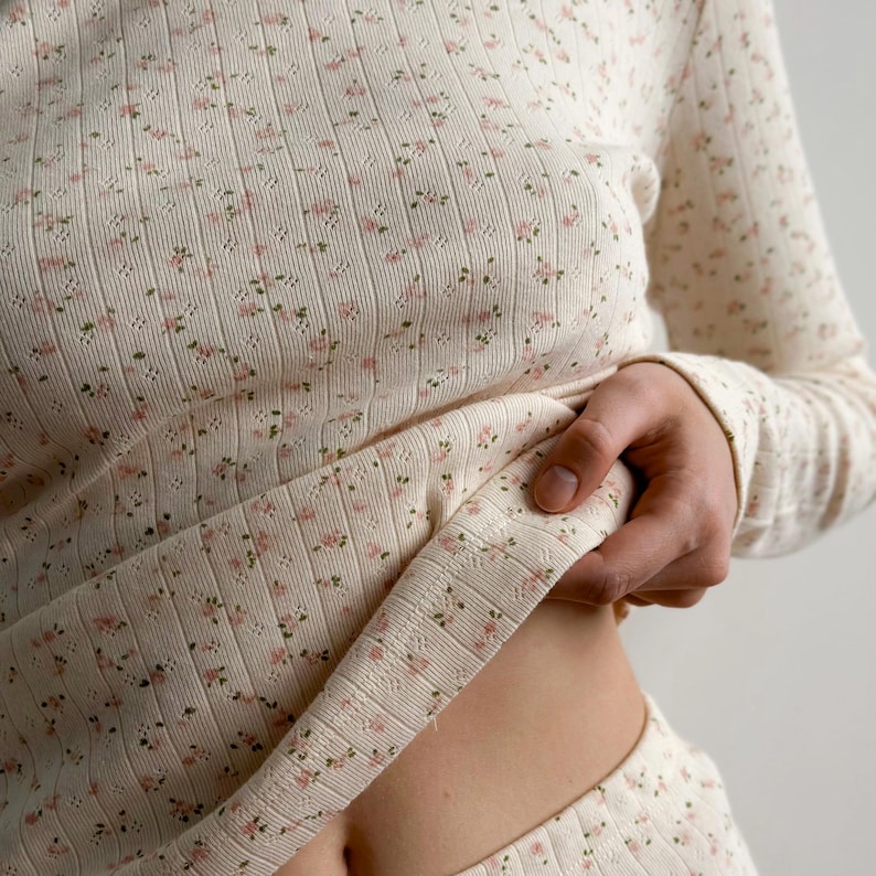 K&ouml;nnte beinhalten: Cremefarbenes lang&auml;rmeliges Oberteil und Hose mit gerippter Struktur und zartem Blumenmuster in Rosa und Gr&uuml;n. Der Stoff ist weich und eignet sich f&uuml;r Loungewear oder Nachtw&auml;sche.