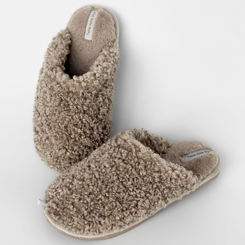 Peut inclure: Une paire de pantoufles moelleuses de couleur taupe. Les pantoufles ont un aspect textur&eacute; et boucl&eacute; et un int&eacute;rieur doux et moelleux. L'&eacute;tiquette sur le c&ocirc;t&eacute; de la pantoufle indique "Twins Home Style".