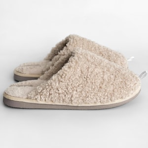 Peut inclure: Une paire de pantoufles beiges et duveteuses. Les pantoufles ont un ext&eacute;rieur doux et textur&eacute; et une semelle grise. Une petite boucle est attach&eacute;e &agrave; l'arri&egrave;re de chaque pantoufle. Les pantoufles sont con&ccedil;ues pour une utilisation en int&eacute;rieur.