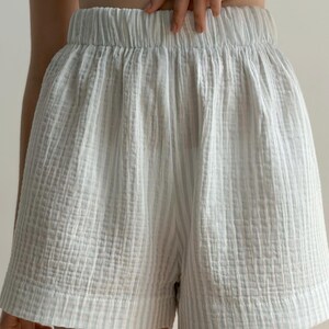 May include: Light blue and white striped shorts with an elastic waistband. The shorts are made of a textured fabric and have a relaxed fit. The shorts are a casual style and suitable for warm weather.
