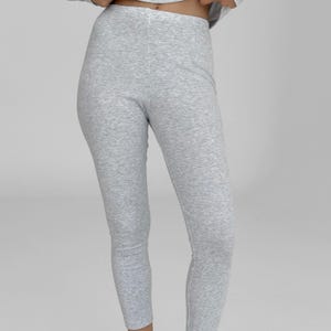 Puede incluir: Leggings acanalados de color gris claro. Los leggings están hechos de un material suave y elástico y tienen un diseño ajustado. La tela tiene una apariencia texturizada. Los leggings son de color sólido y parecen cómodos.
