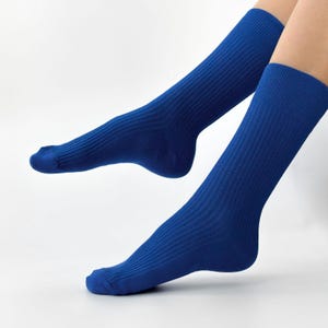 May include: Two blue ribbed socks are shown against a white background. The socks are a solid, vibrant blue color and appear to be made of a soft, comfortable material. The ribbed texture is clearly visible, adding visual interest to the design.