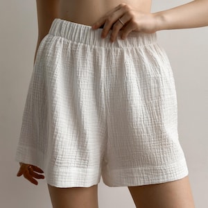 May include: White, textured shorts with an elastic waistband. The shorts have a loose, comfortable fit and a crinkled fabric appearance. The shorts are made of a lightweight material, perfect for warm weather.