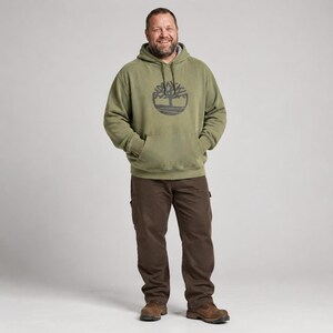 Puede incluir: Una sudadera con capucha de color verde oliva que presenta un logotipo de árbol circular de color gris oscuro en el pecho, combinada con pantalones de color marrón oscuro y botas de cuero marrón. Incluye un bolsillo tipo canguro.