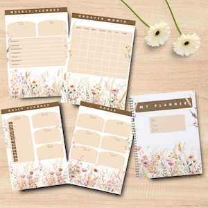 Op de afbeelding: Een set papieren planners inclusief een weekplanner, ongedateerde maandkalender, dagplanner, doelenblad en een spiraalgebonden notitieboek. Elke pagina heeft een bruine koptekst en een onderrand met aquarel veldbloemen in zachte roze en bruine tinten.