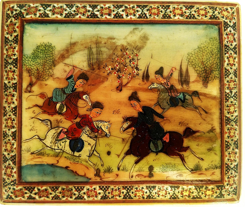 May include: A rectangular, hand-painted miniature painting depicting a polo match. The artwork features several figures on horseback, engaged in a game, with a detailed border. The color palette includes earth tones, with accents of red, blue, and white.